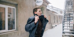 Man walking outdoors in winter pulling his jacket collar up against the cold