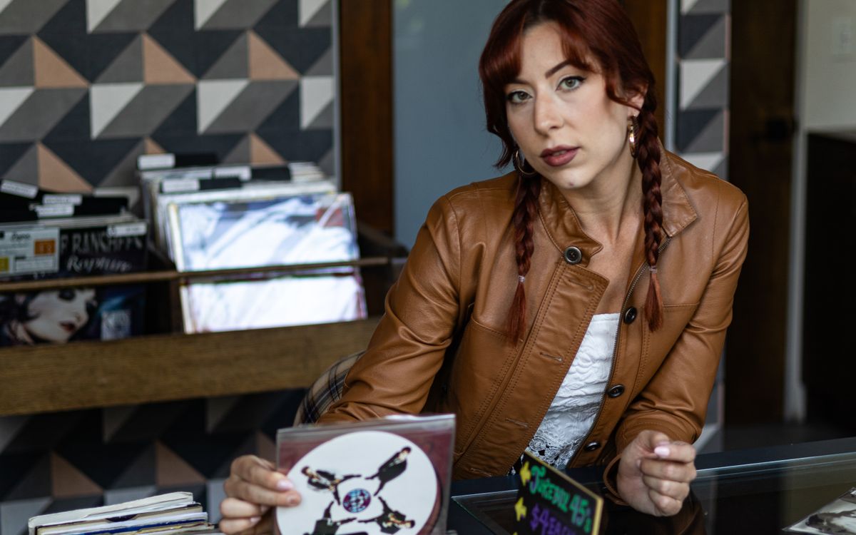 Woman in a leather jacket browsing vinyl records in a vintage music store