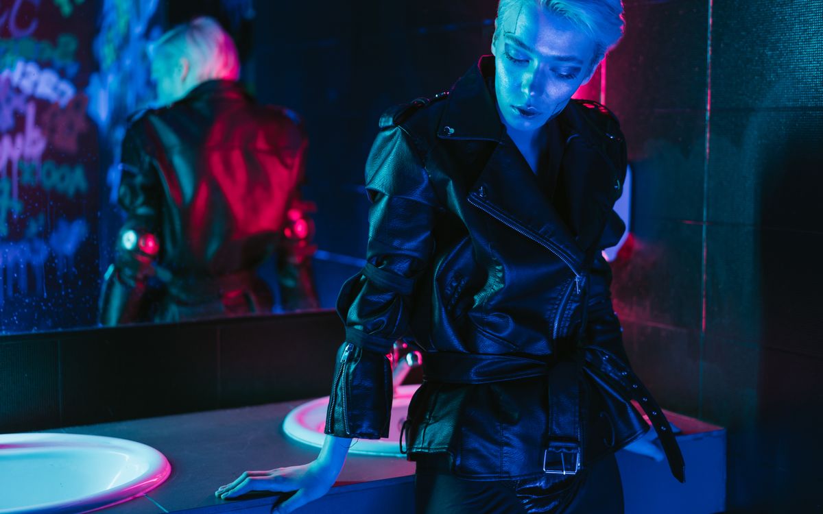 A person checking the fit of a black leather jacket in a mirror