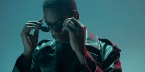 Stylish man adjusting his sunglasses while wearing a leather jacket