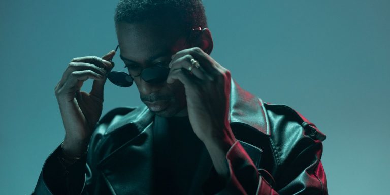 Stylish man adjusting his sunglasses while wearing a leather jacket